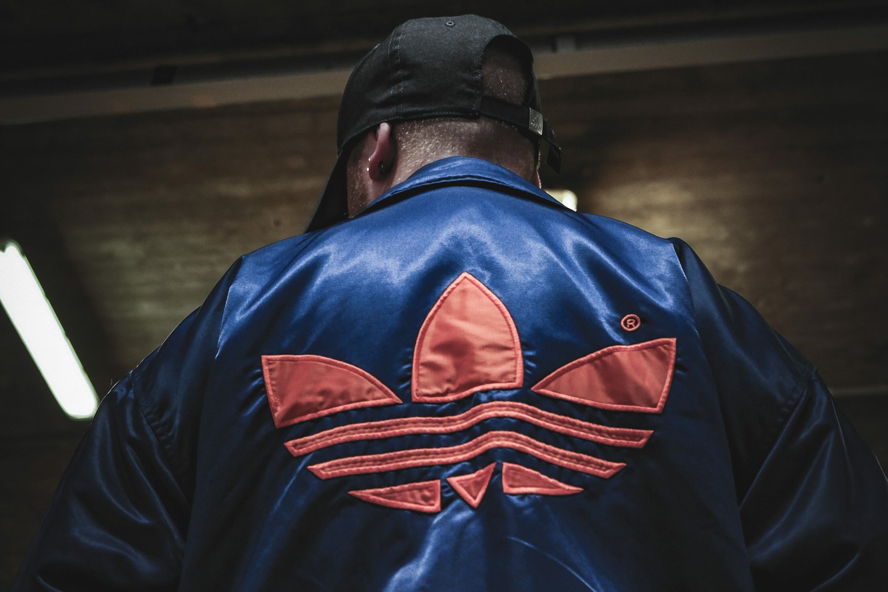 Streetstyle-Portrait, Mann in Adidas-Bomberjacke von hinten