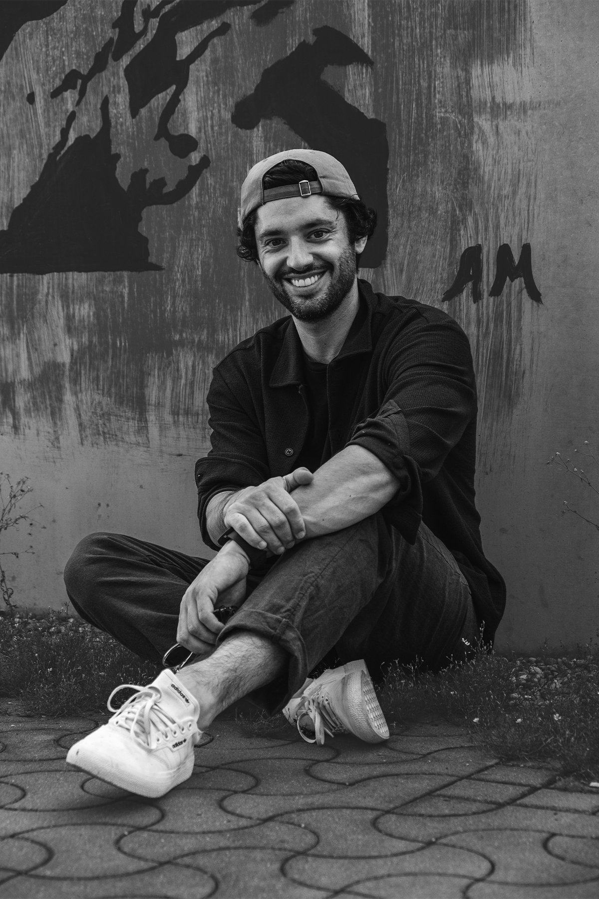 Schwarzweiß-Portrait eines Mannes vor einer Graffiti-Wand