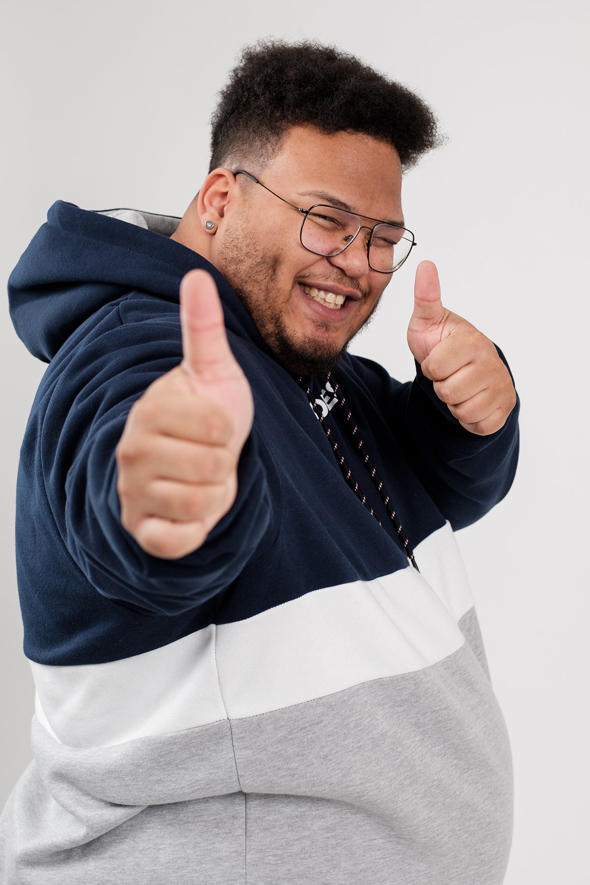 Studio-Portrait eines Mannes im Hoodie mit Daumen hoch